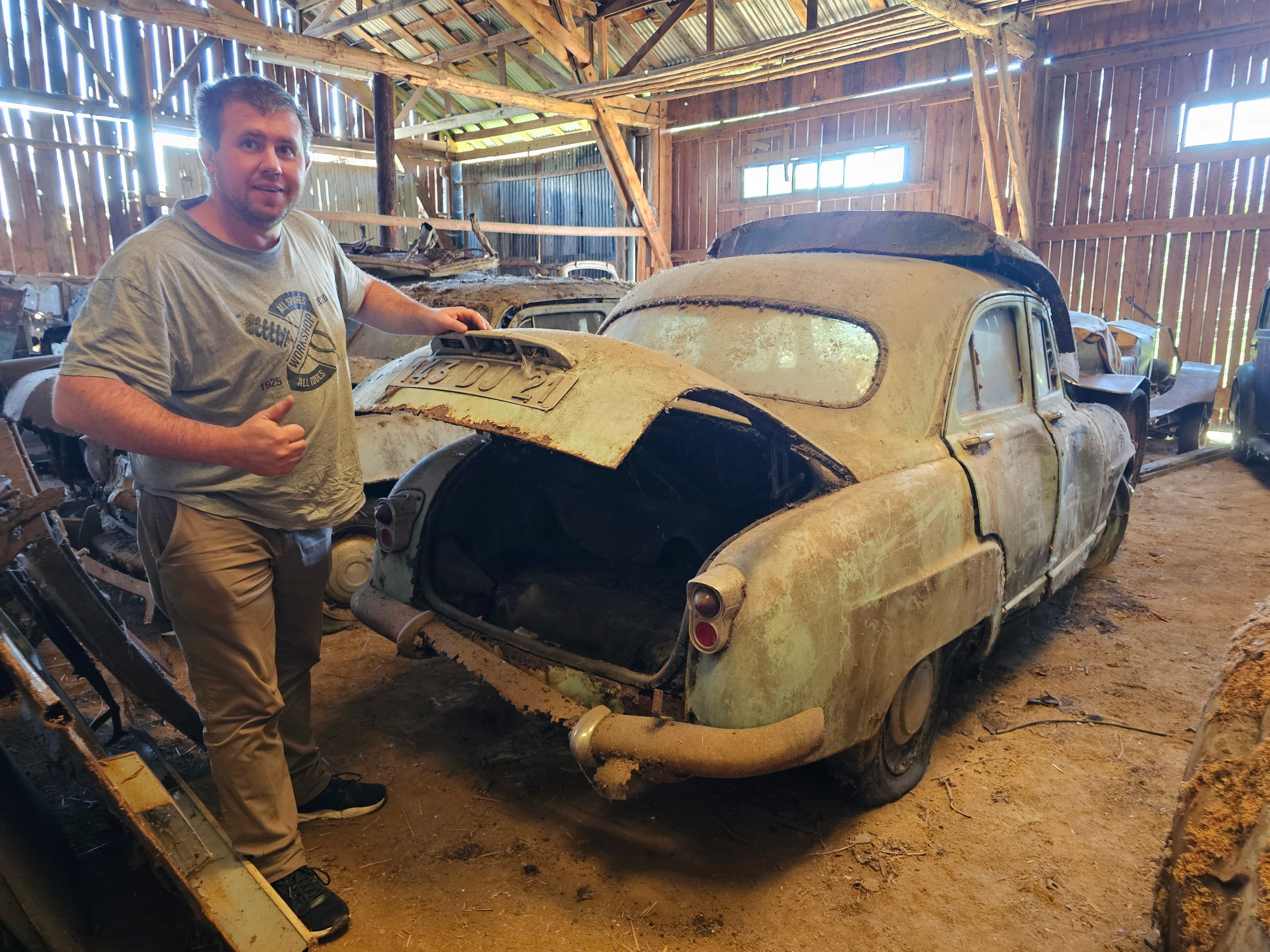 Founder of Mancave Artisan standing beside a rescued classic car inside the vehicle archive